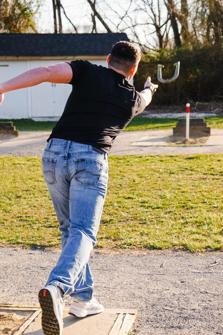 A man in black shirt and jeans playing frisbee.