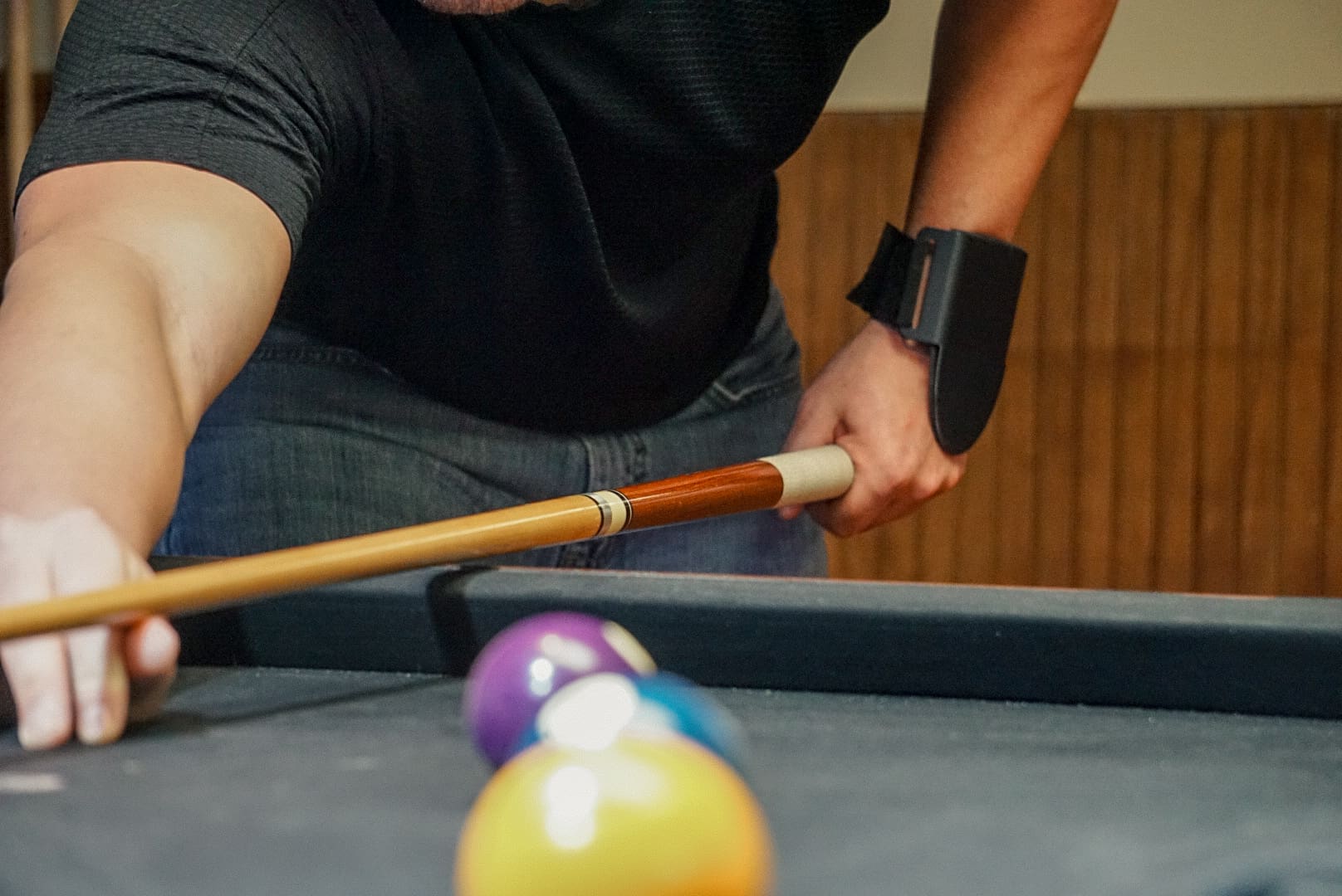 A man holding a pool cue over three balls.