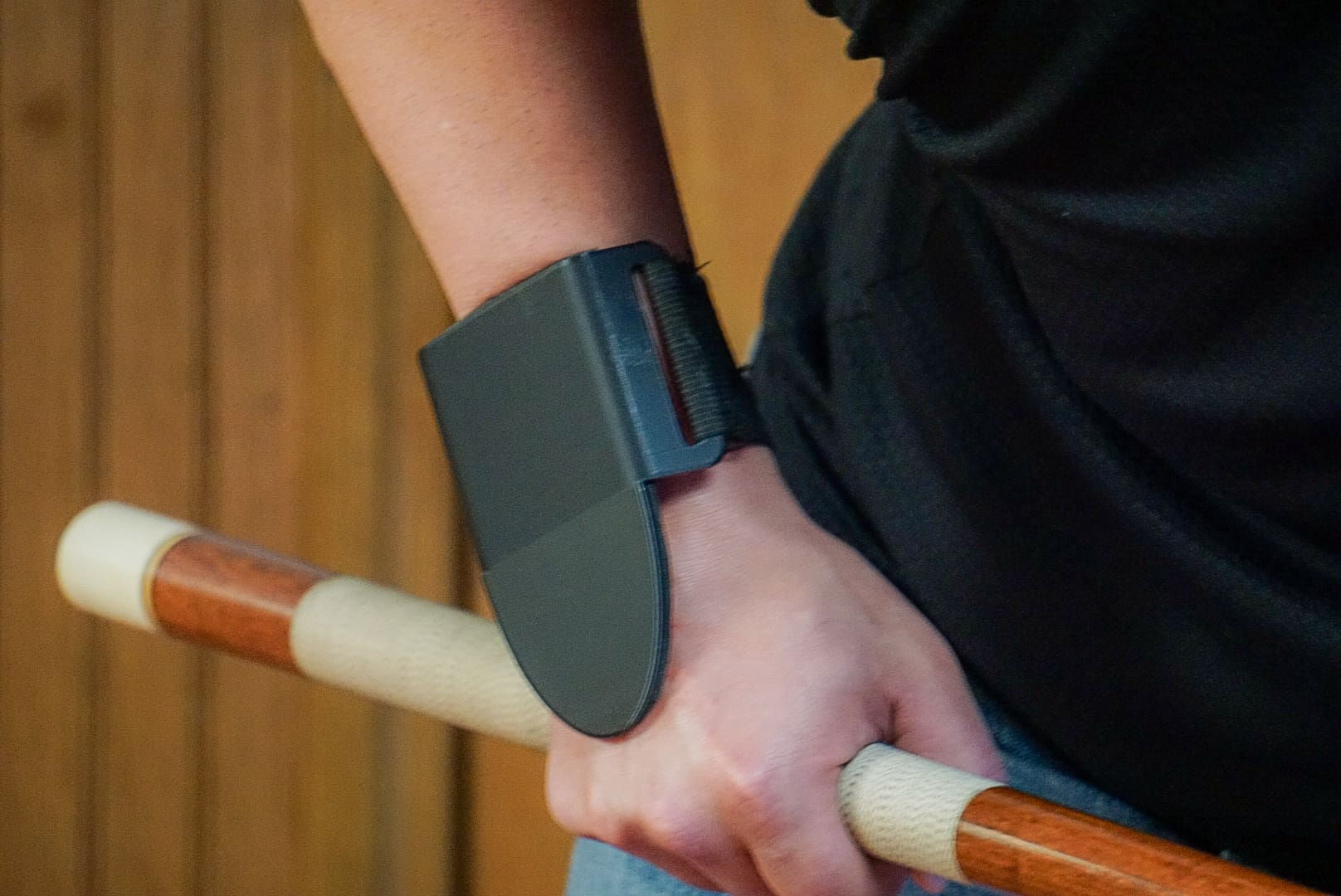 A person wearing a black wrist band holding onto a bar