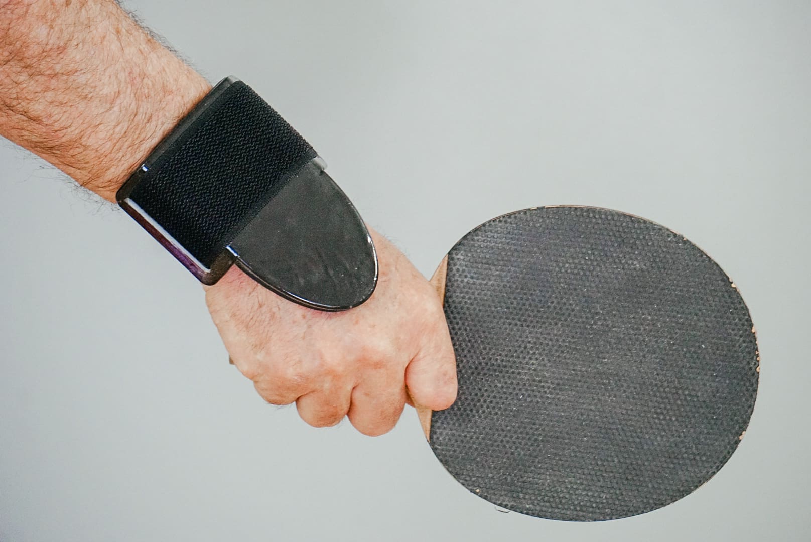 A person holding a ping pong paddle in their hand.