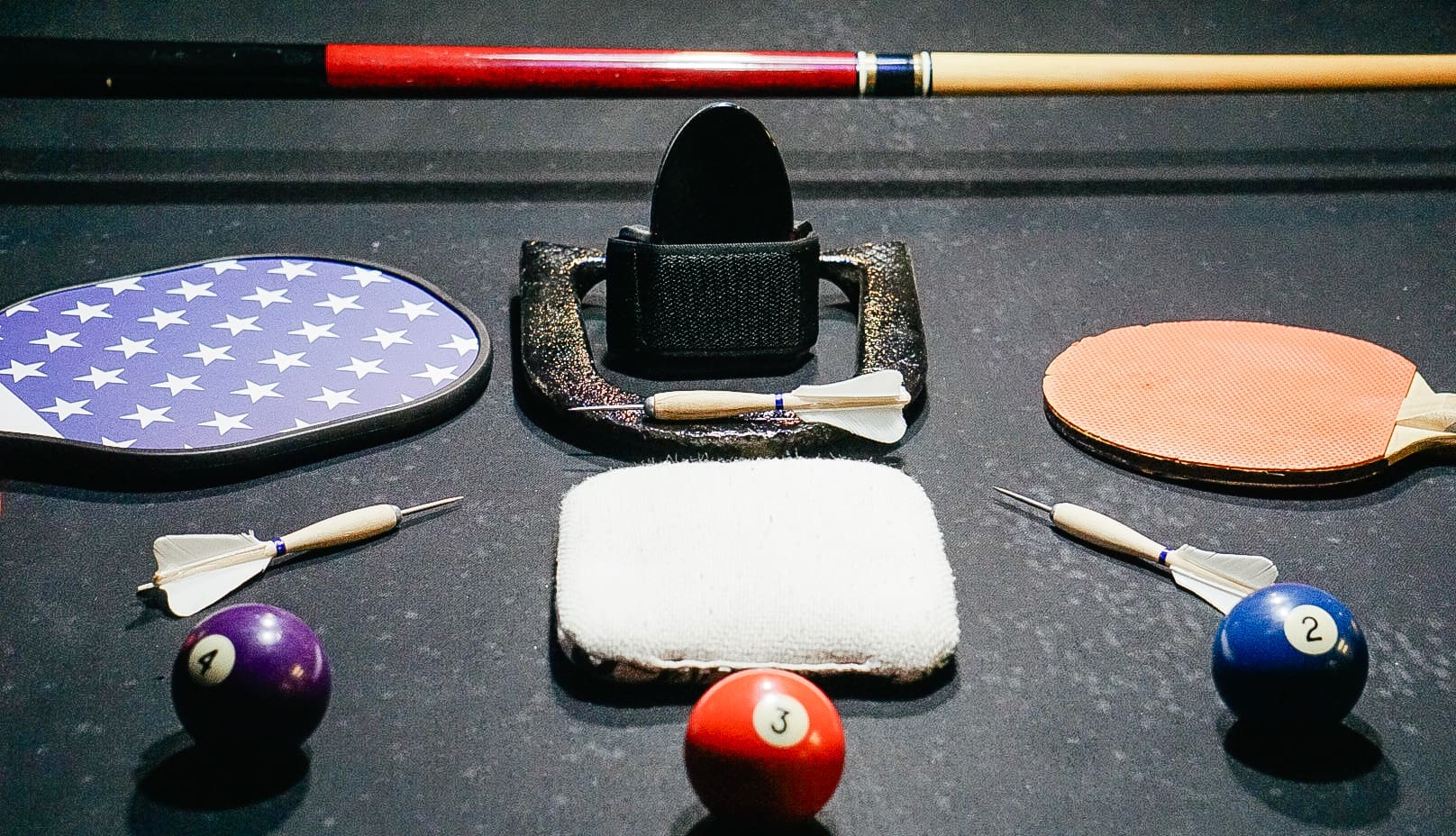 A table with pool balls, cue sticks and other items.